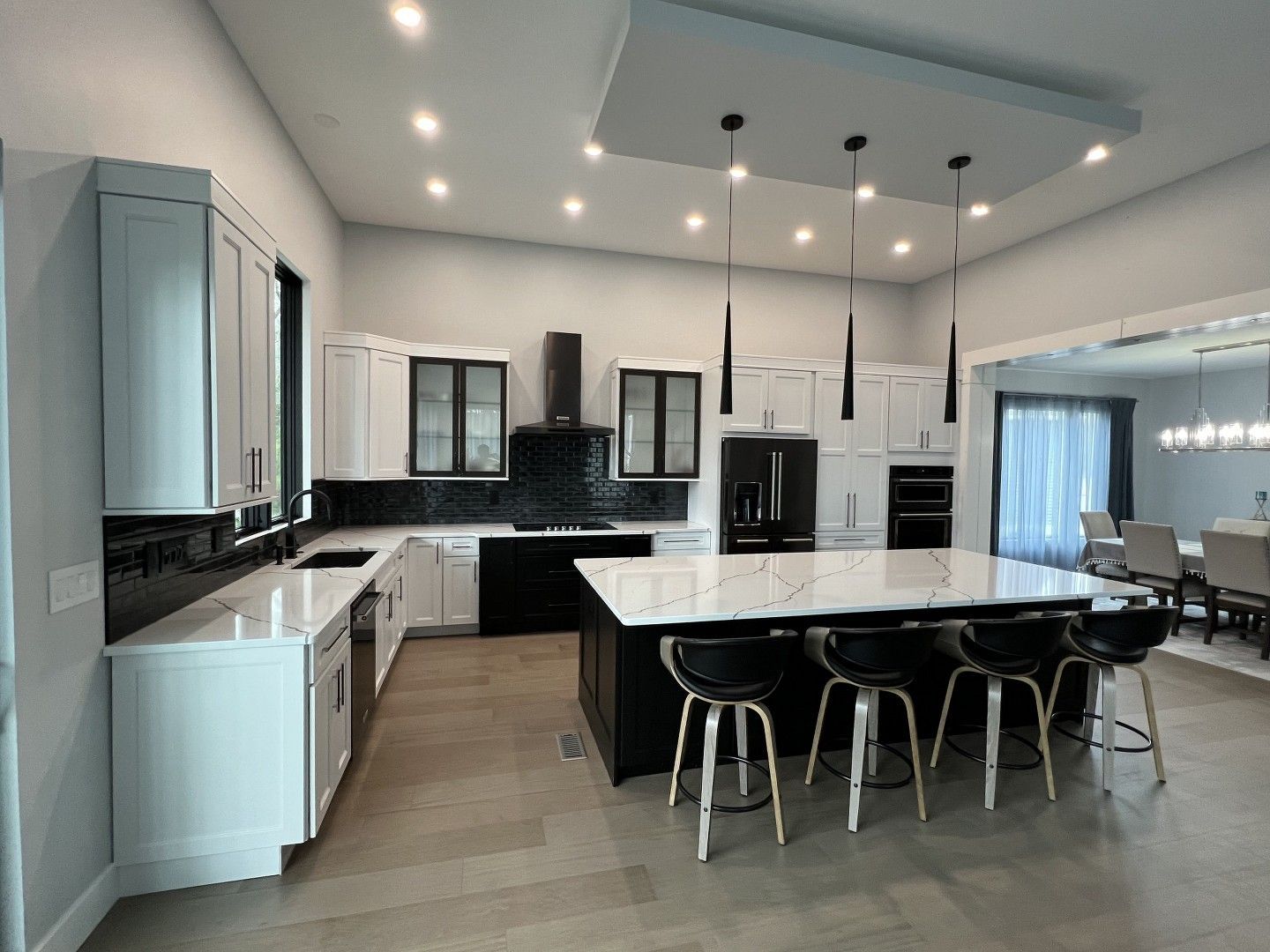 A kitchen with white cabinets , black appliances , and a large island.