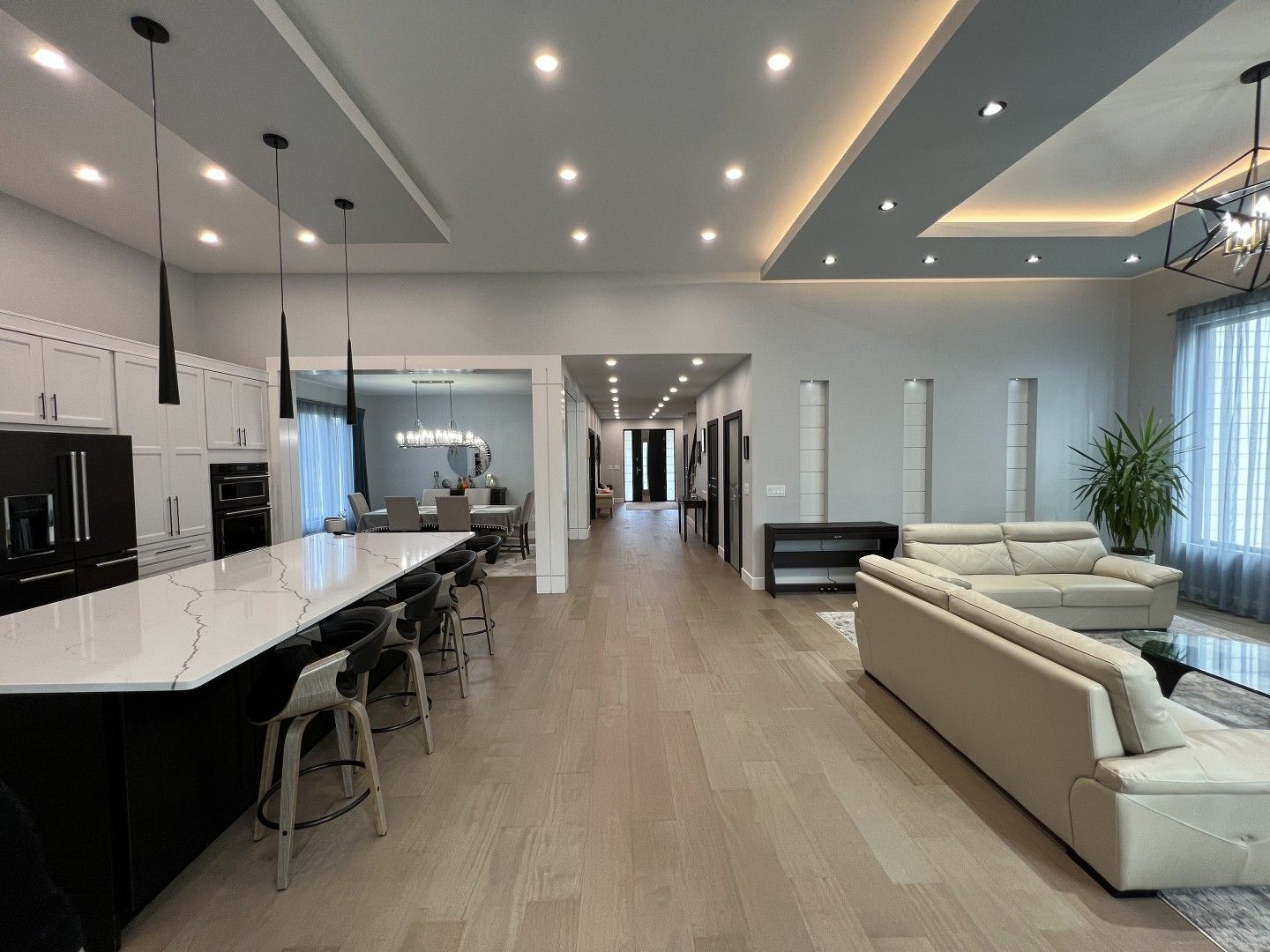 A living room with a couch , table , chairs and a kitchen.