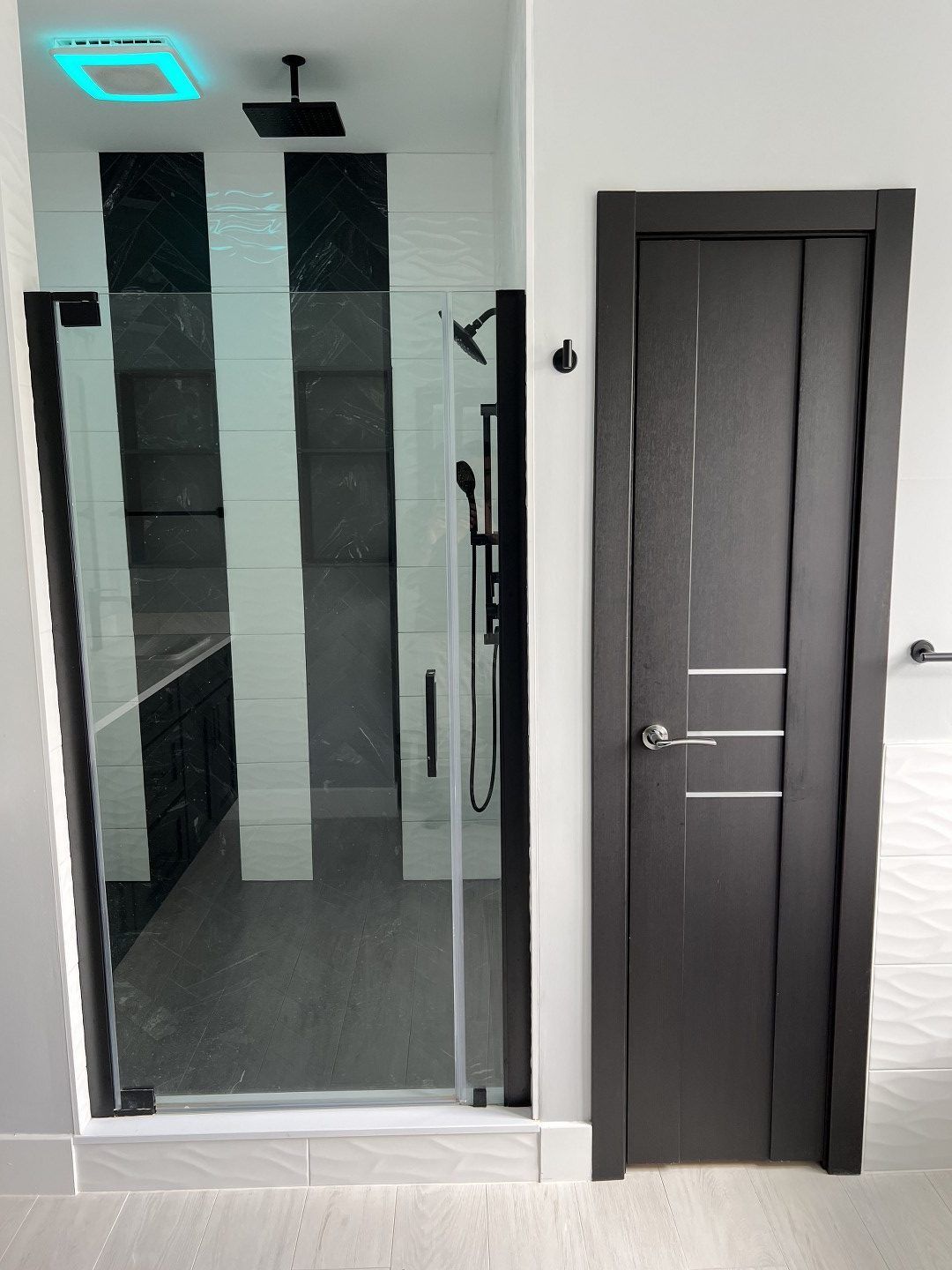 A bathroom with a shower and a black door