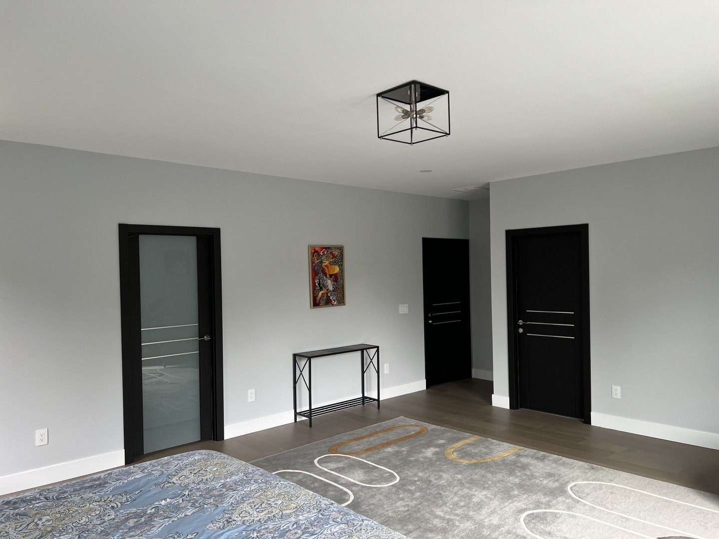 A living room with gray walls and black doors and a rug.