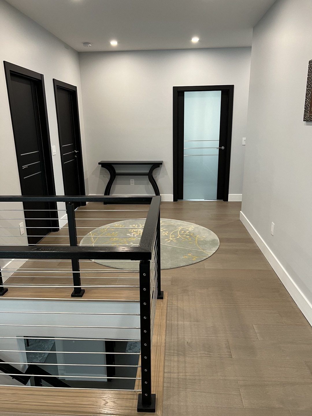 A hallway with a staircase and a table in the middle of it.