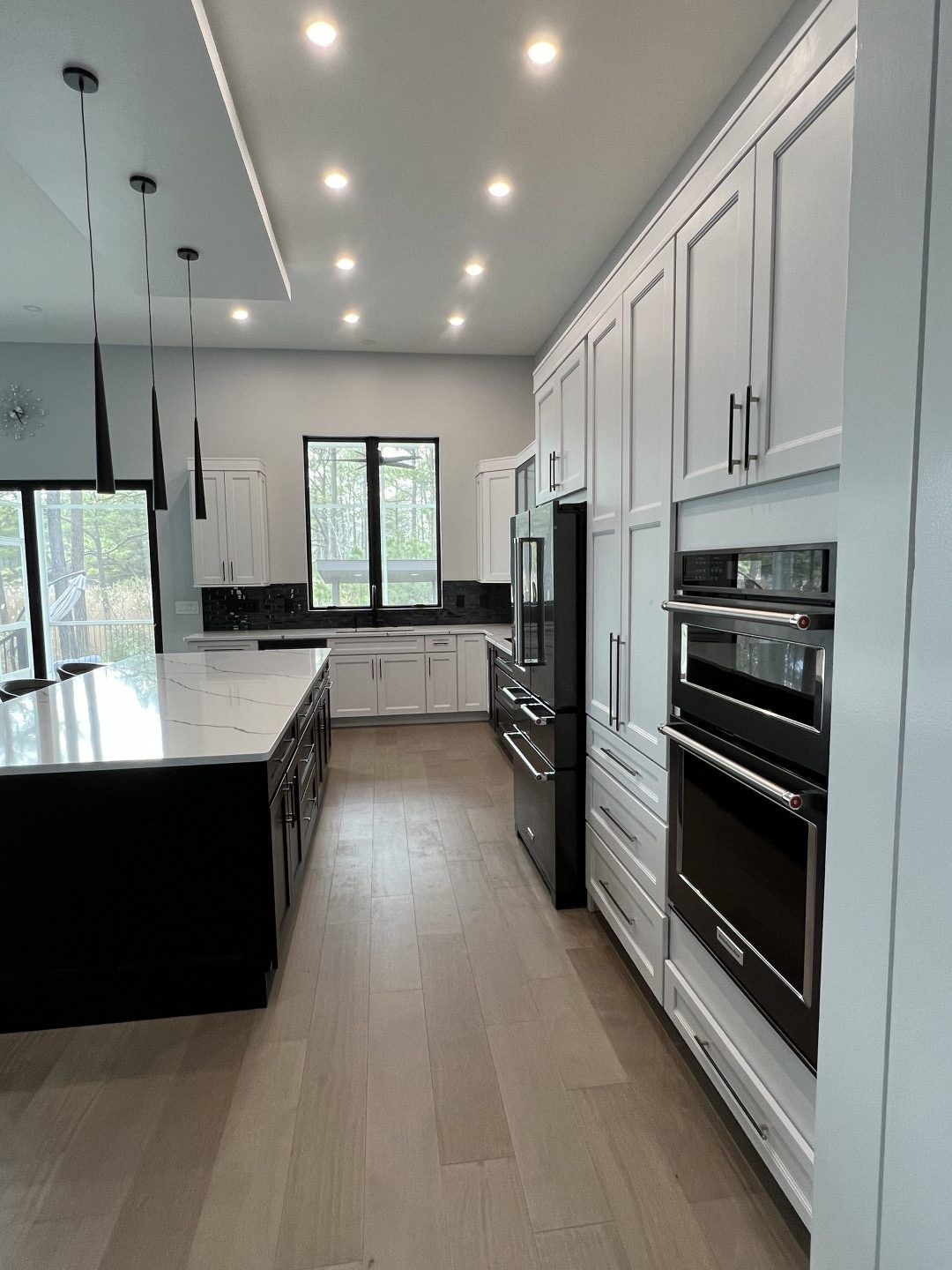 A kitchen with white cabinets , black appliances , and a large island.
