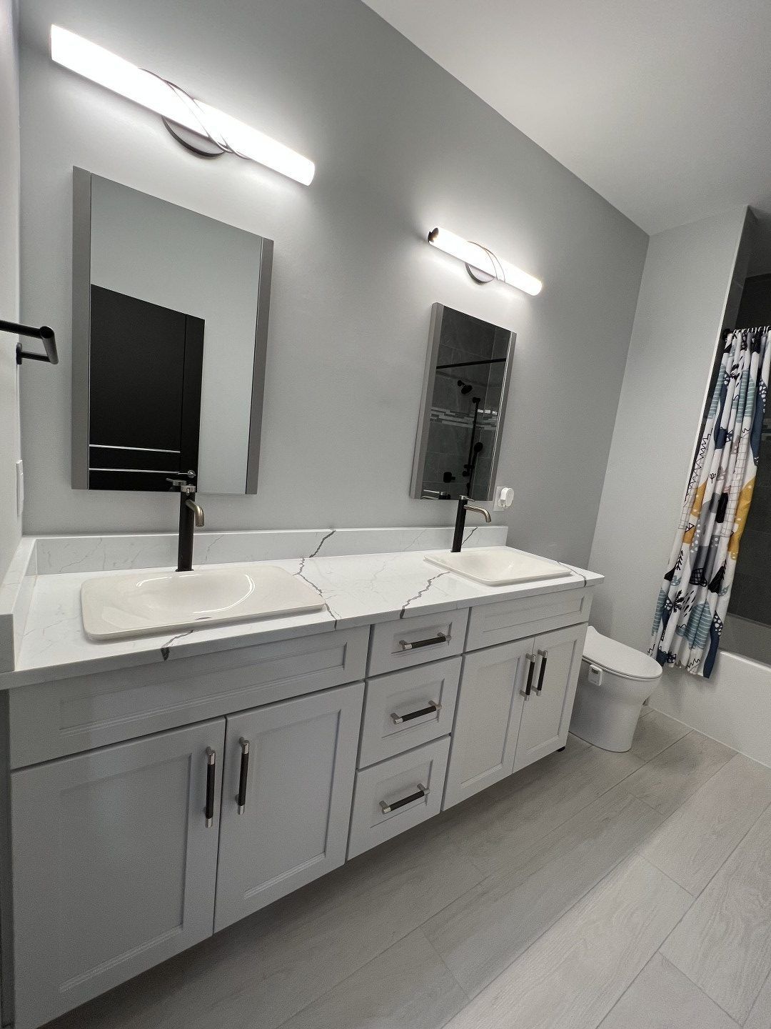 A bathroom with two sinks , a toilet , and a shower curtain.