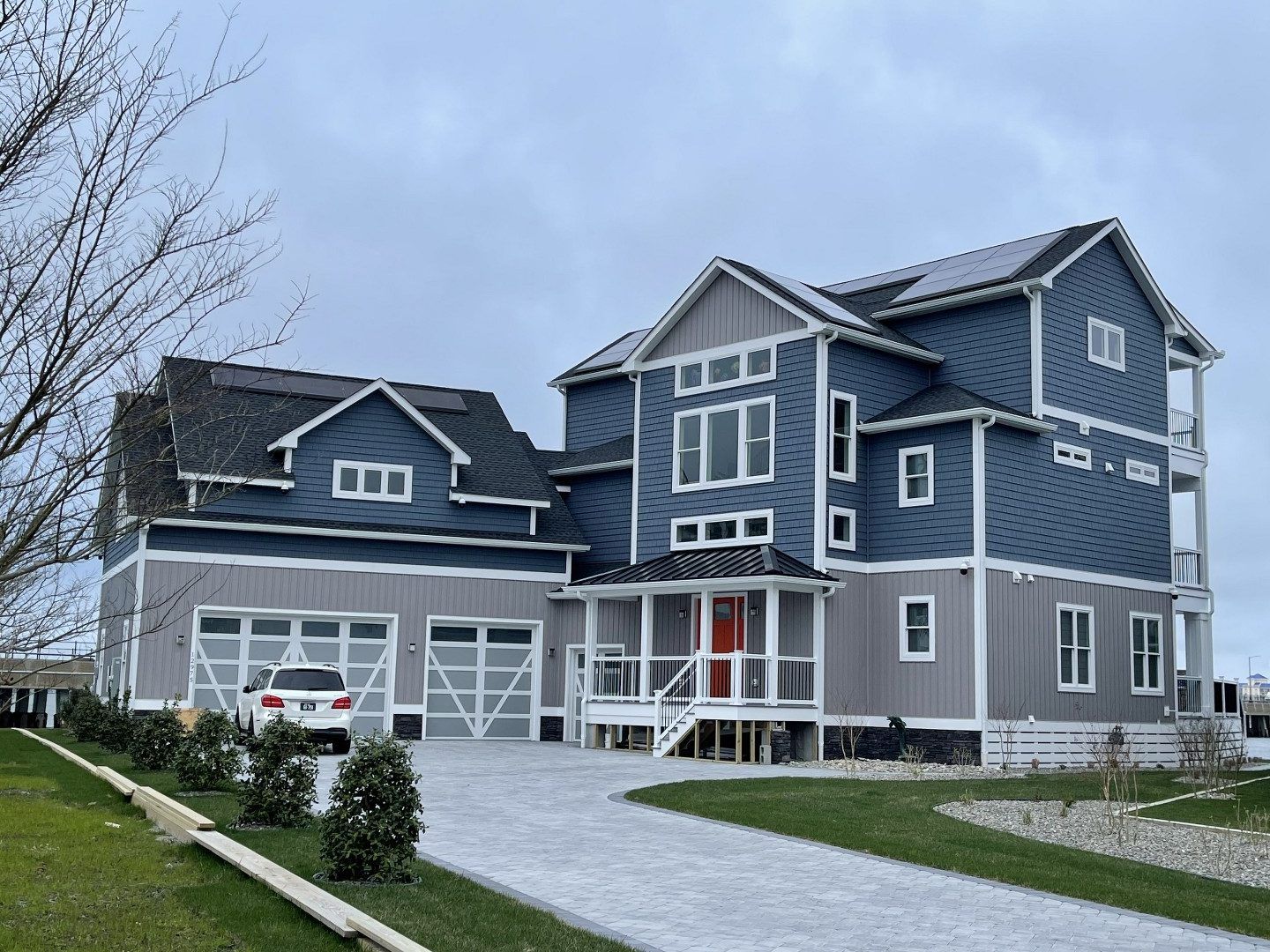 A large blue and gray house with a car parked in front of it.