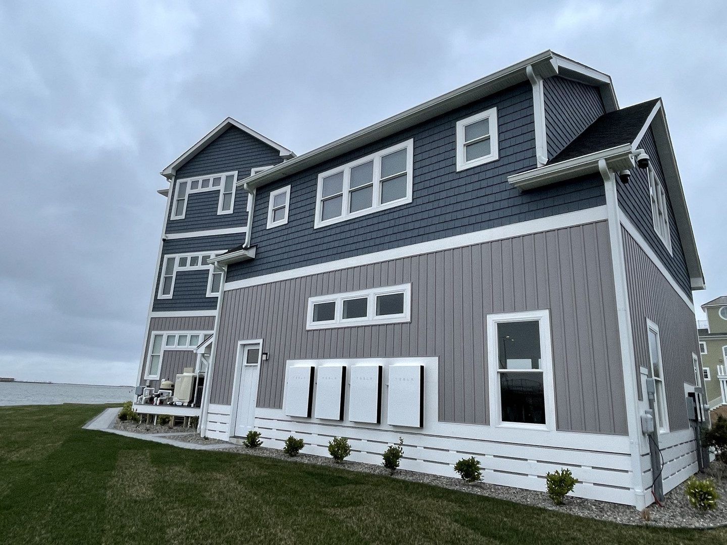 A large house with a lot of windows is sitting on top of a lush green field.