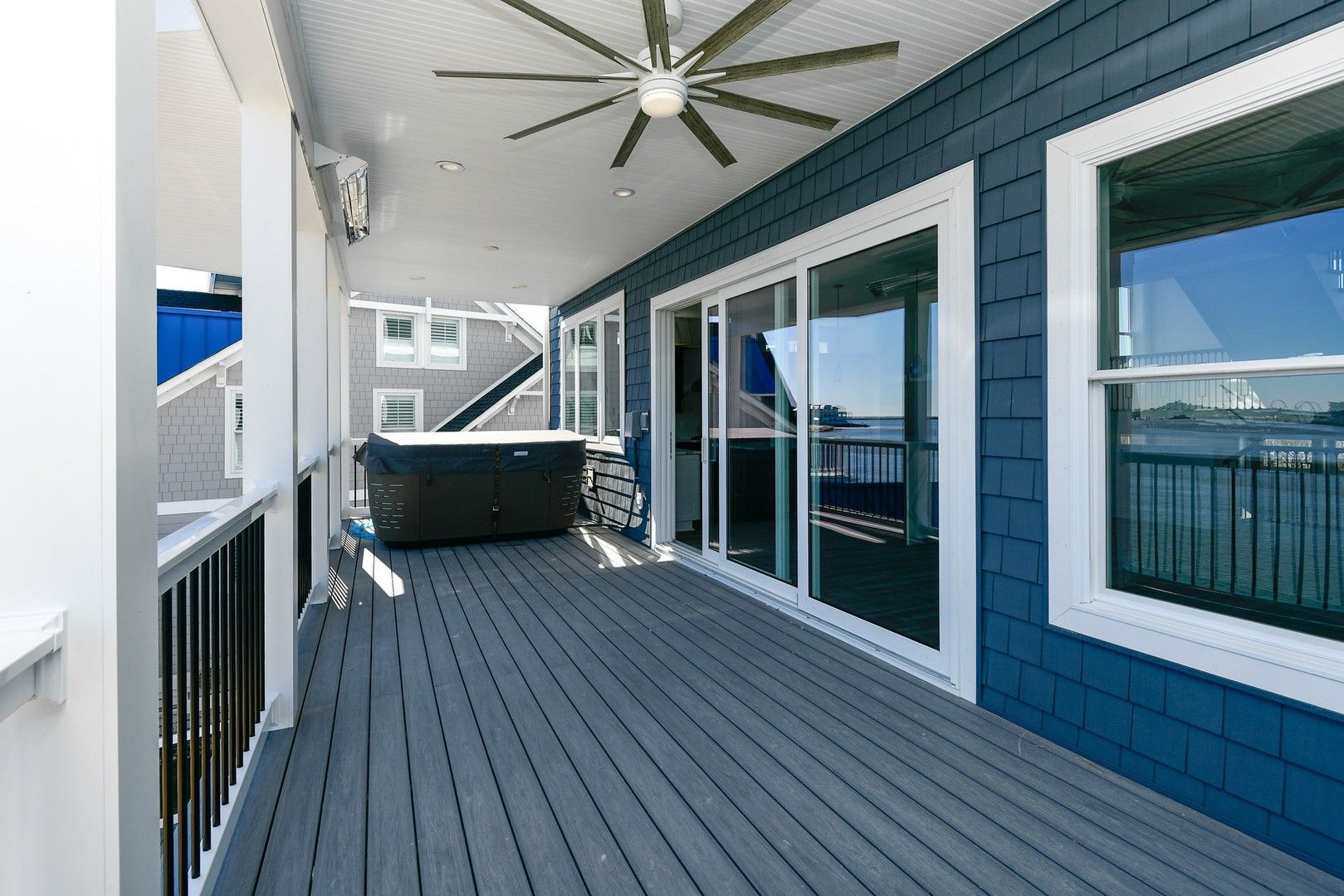 A large deck with a ceiling fan and a hot tub on it.