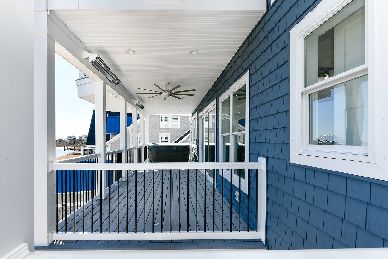 A blue and white house with a large porch and a ceiling fan.