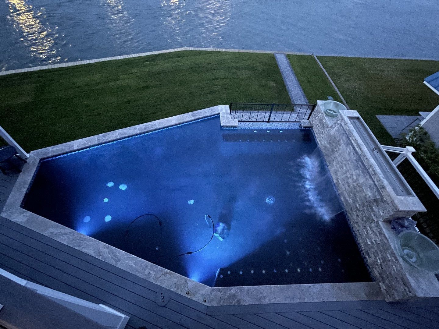 An aerial view of a large swimming pool surrounded by grass and water.