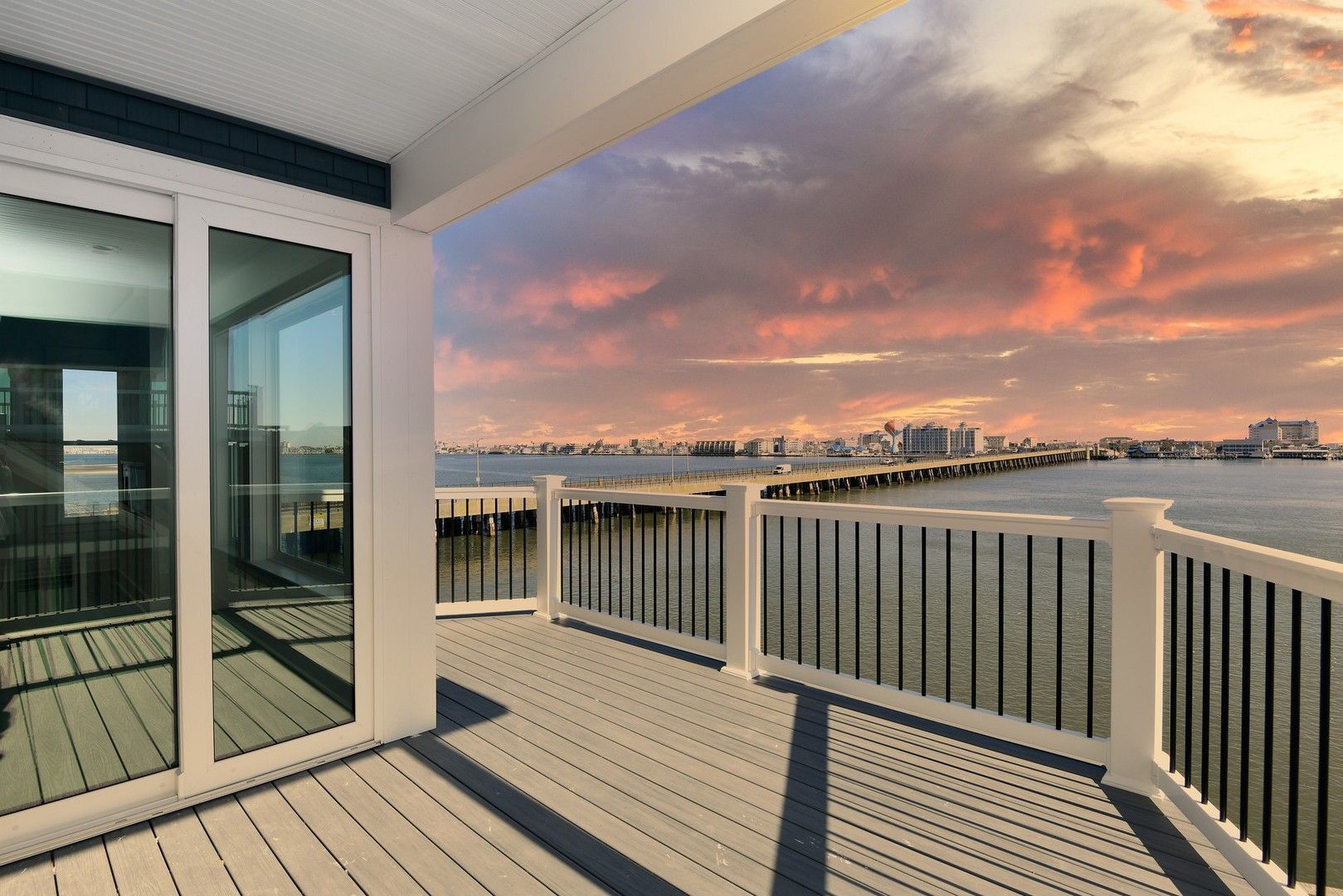 A balcony overlooking a body of water with a sunset in the background.