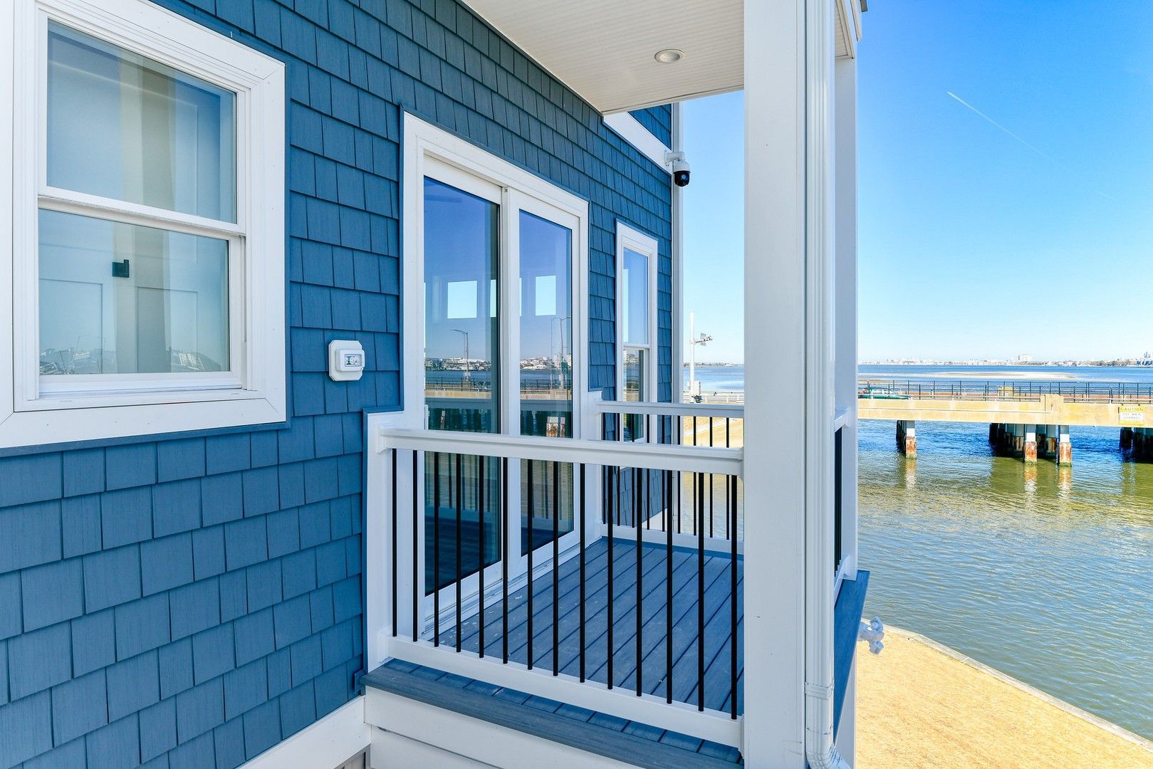 A blue house with a balcony overlooking the ocean.