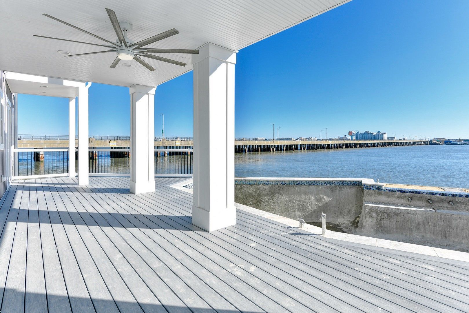 A large deck with a ceiling fan overlooking a body of water