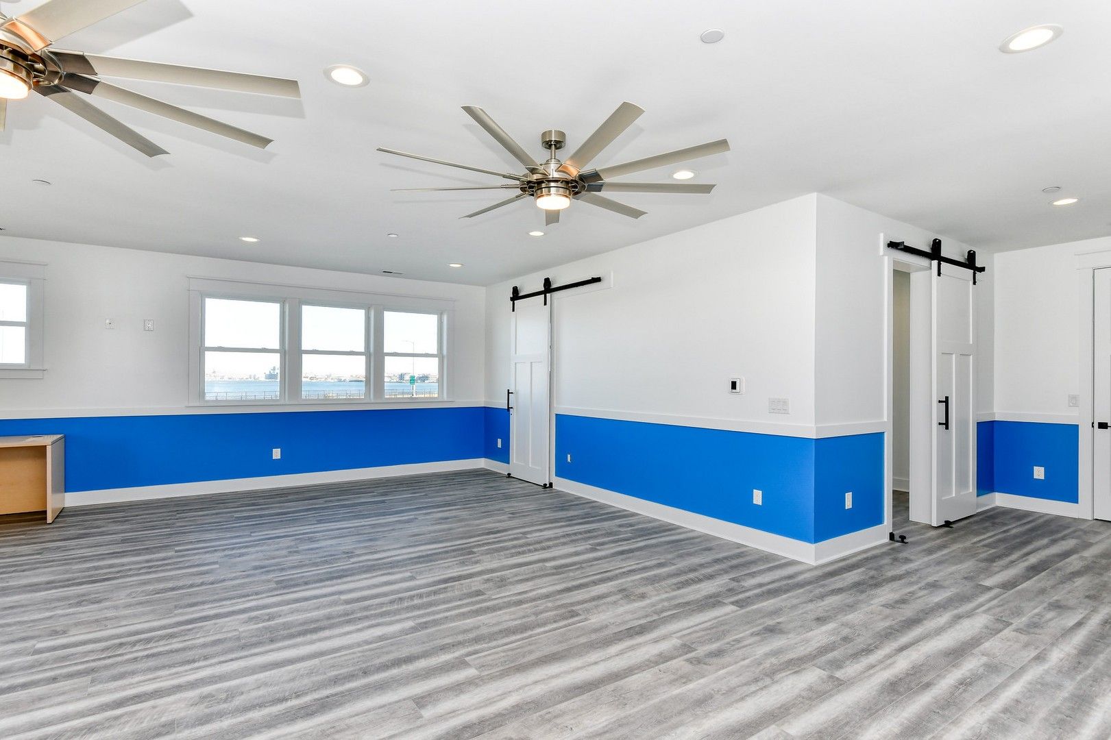 An empty room with blue and white walls and a ceiling fan.