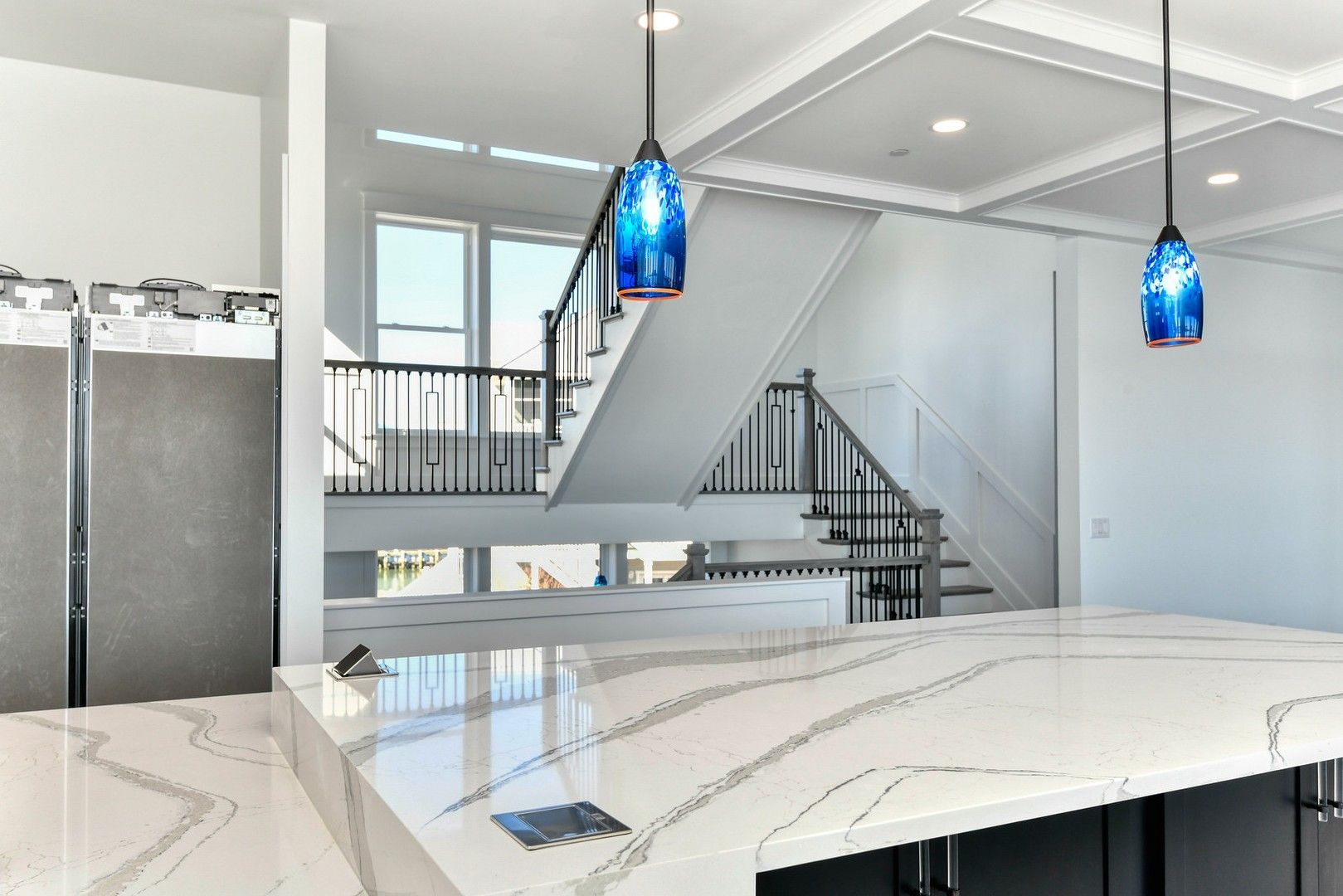 A kitchen with a large island and stairs in the background.