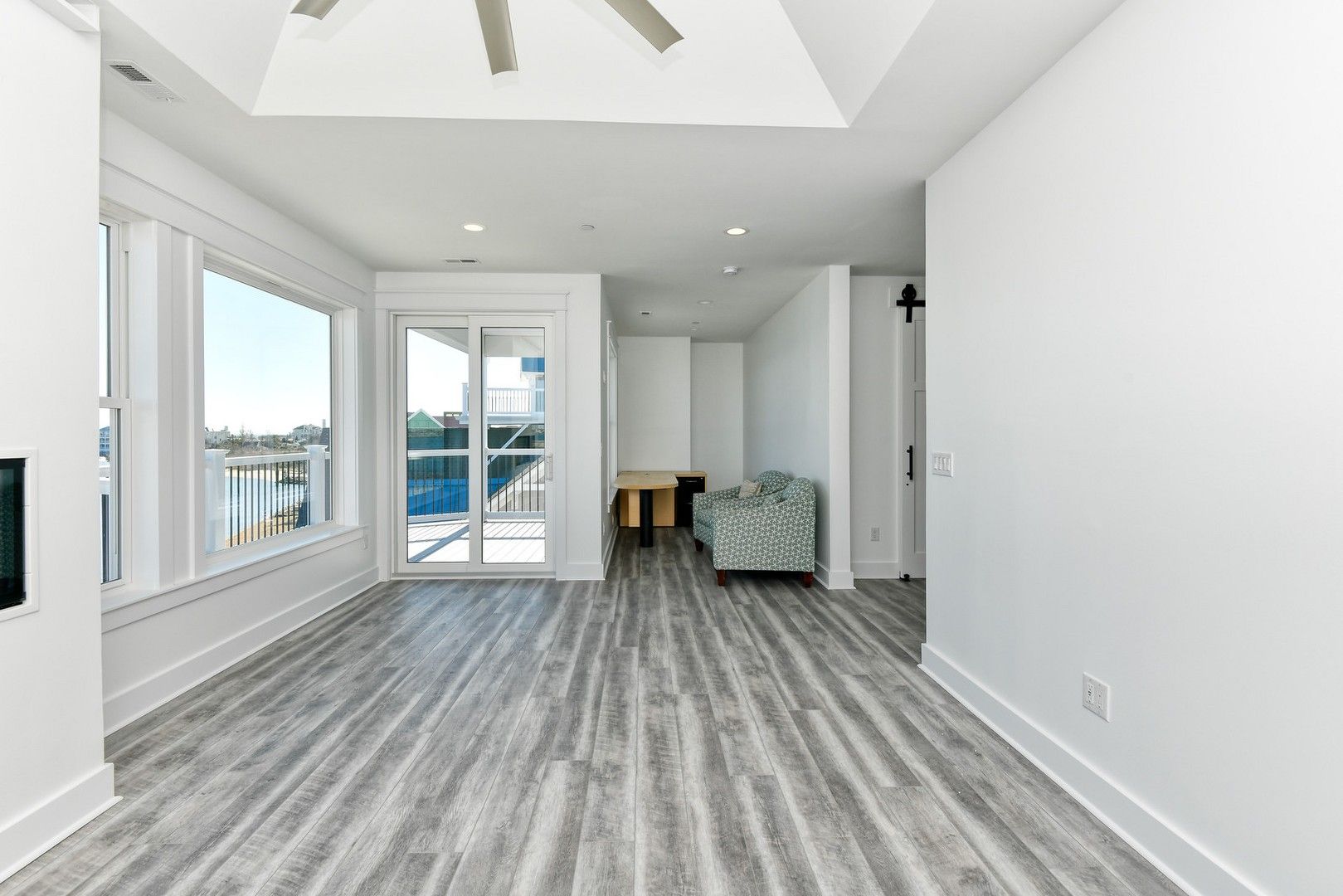An empty living room with hardwood floors and a ceiling fan.