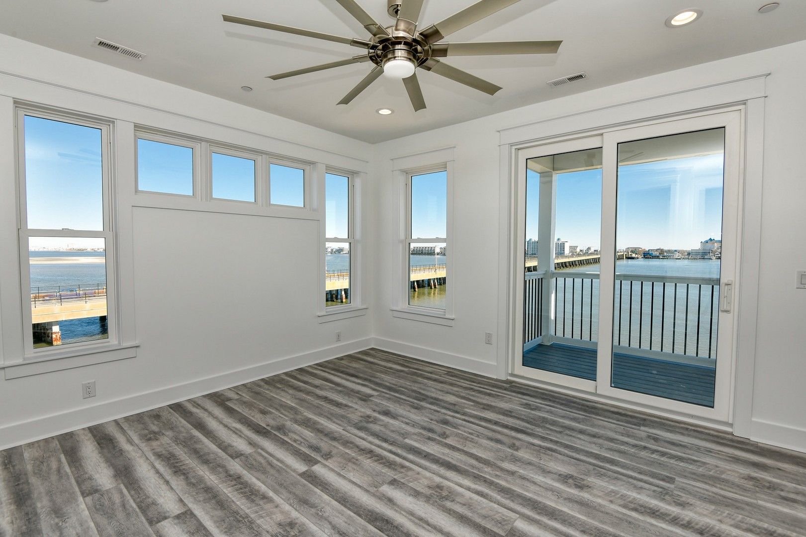 An empty room with a ceiling fan and sliding glass doors.