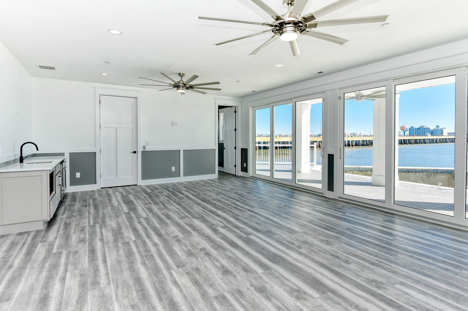 A large empty room with a lot of windows and a ceiling fan.