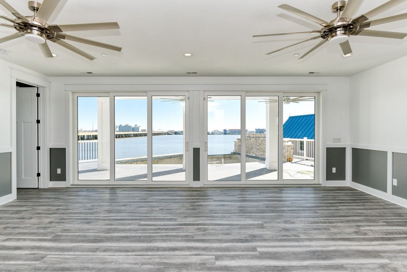 An empty living room with a lot of windows and a ceiling fan.