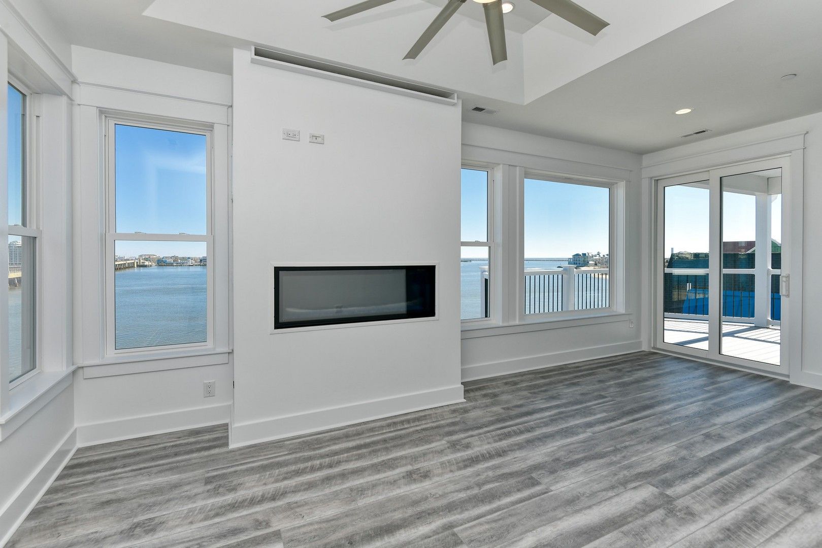 A living room with a fireplace and a lot of windows overlooking the water.