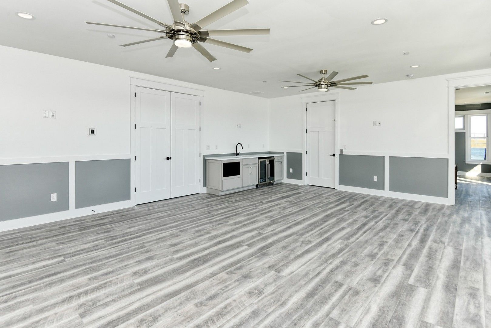 A large empty room with a ceiling fan and wooden floors.