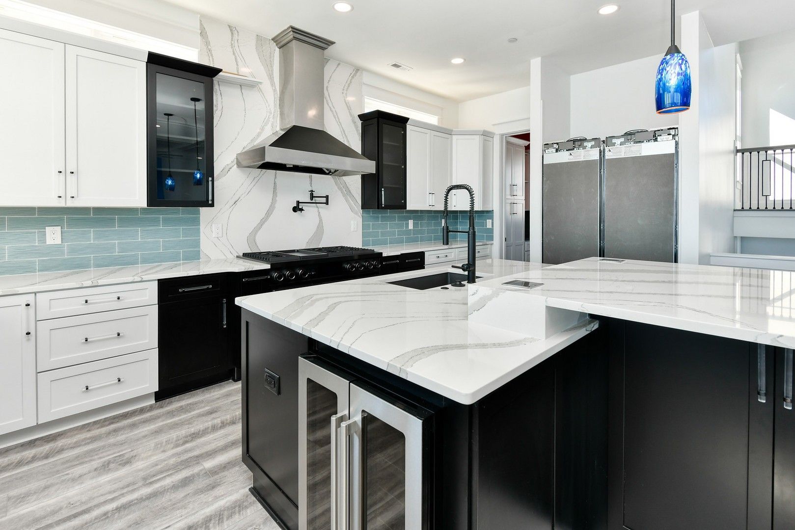 A kitchen with black and white cabinets , granite counter tops , stainless steel appliances and a large island.