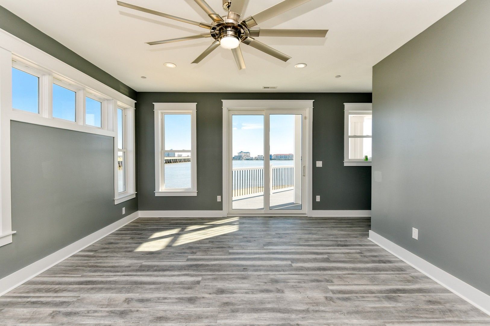 An empty living room with a ceiling fan and sliding glass doors.