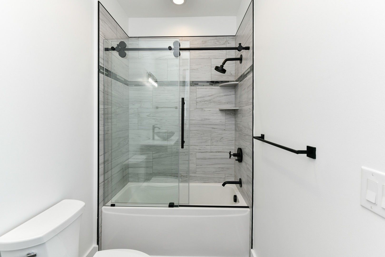 A bathroom with a sliding glass shower door and a bathtub.