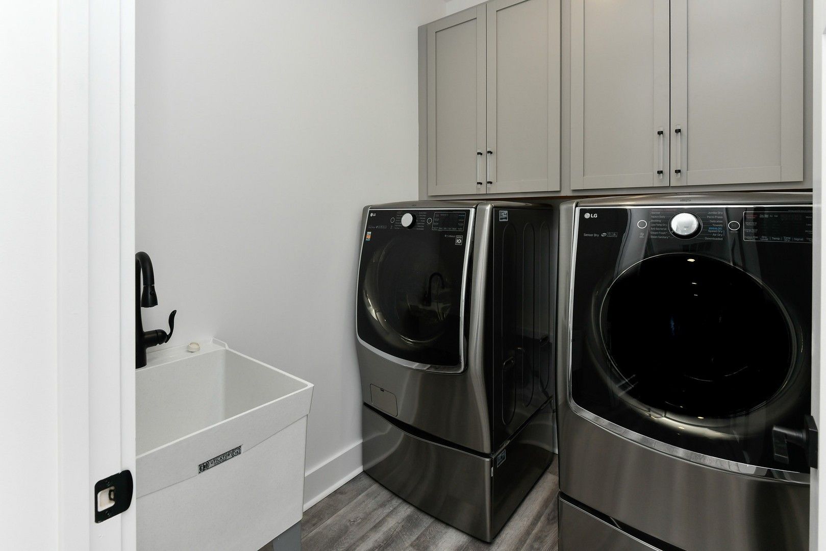 A laundry room with two stainless steel washers and dryers.