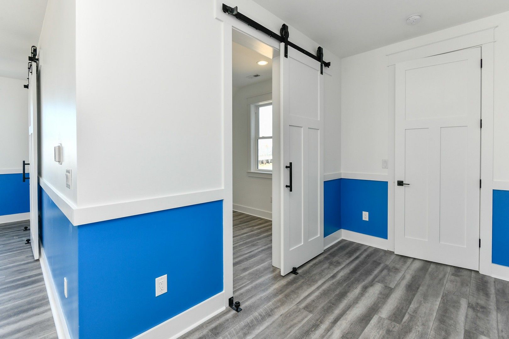 A room with blue and white walls and a sliding barn door.