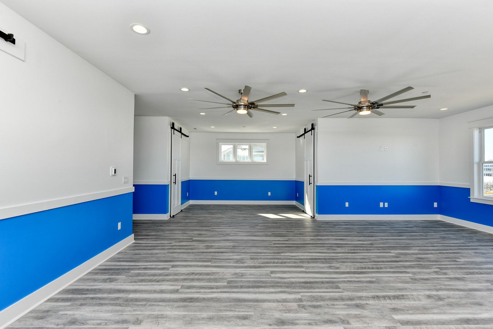 An empty room with blue and white walls and ceiling fans