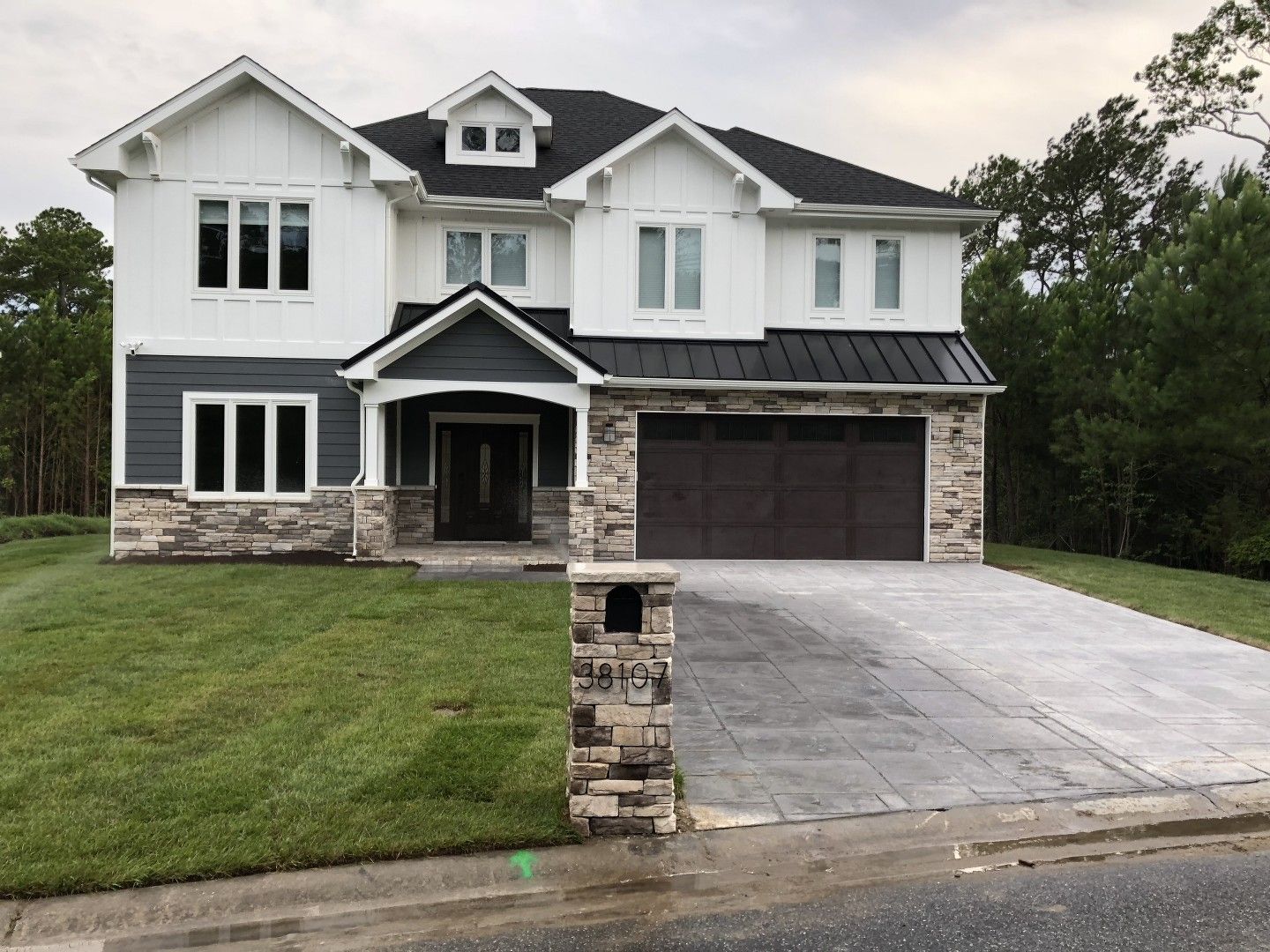 A large white house with a black roof is sitting on top of a lush green lawn.
