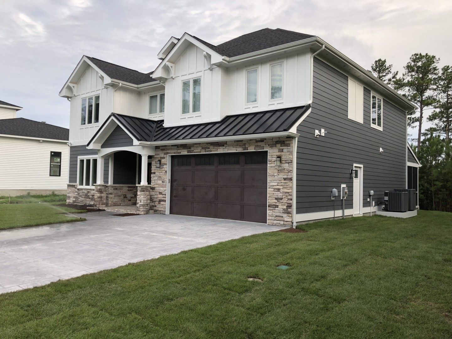 A large house with a brown garage door is sitting on top of a lush green lawn.