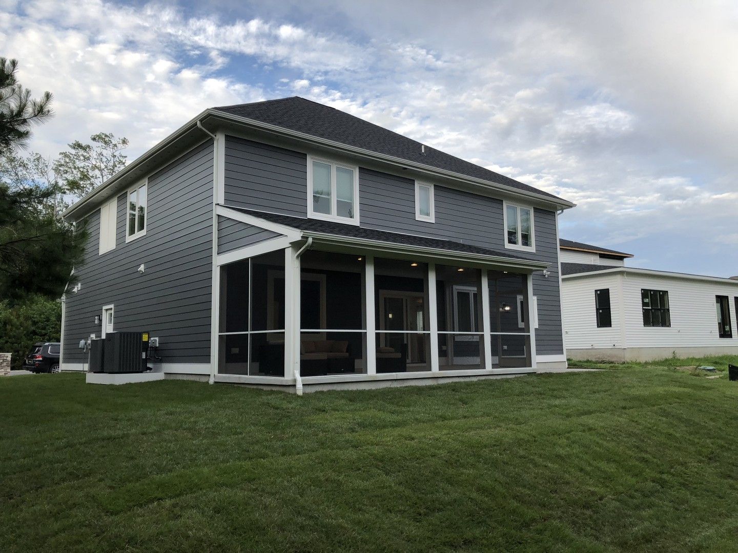 A large house with a screened in porch in the backyard.