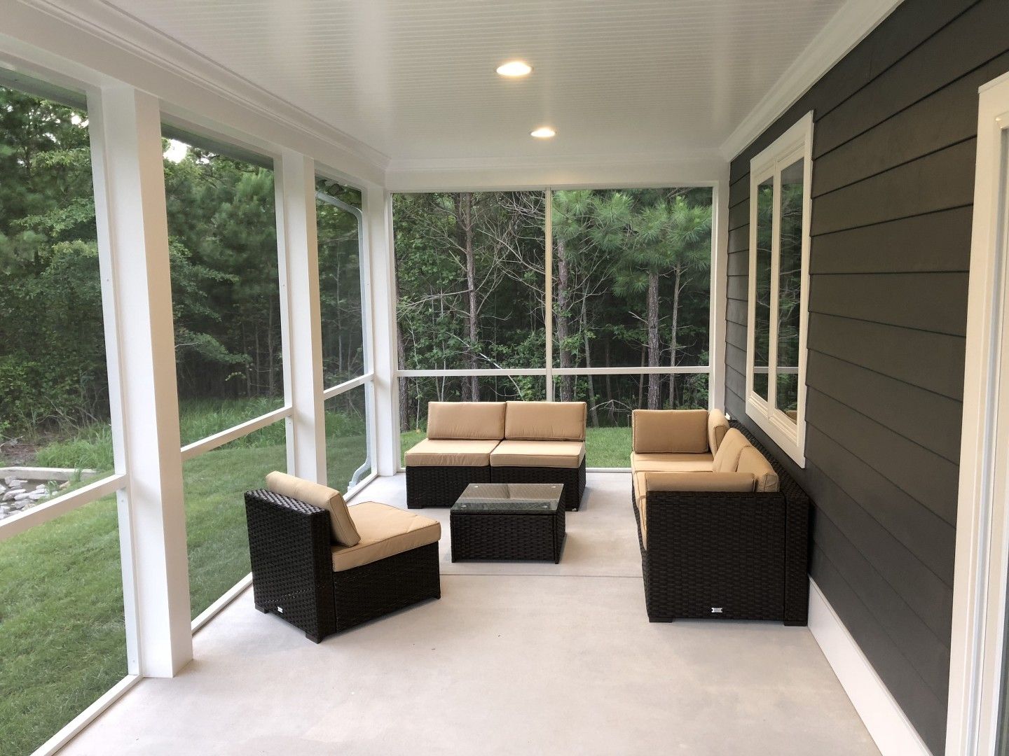 A screened in porch with a couch and chairs