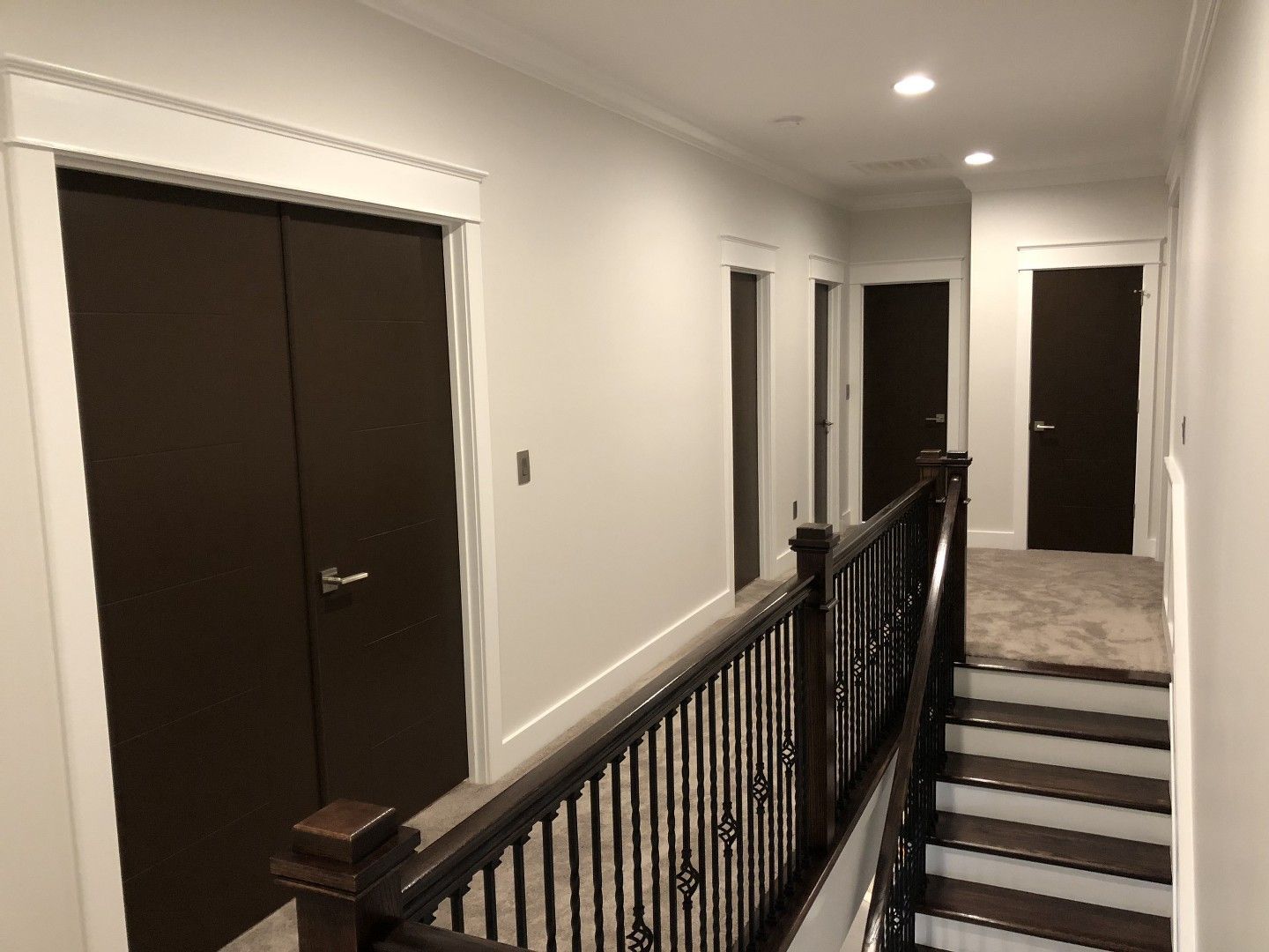 A hallway with stairs and brown doors in a house.
