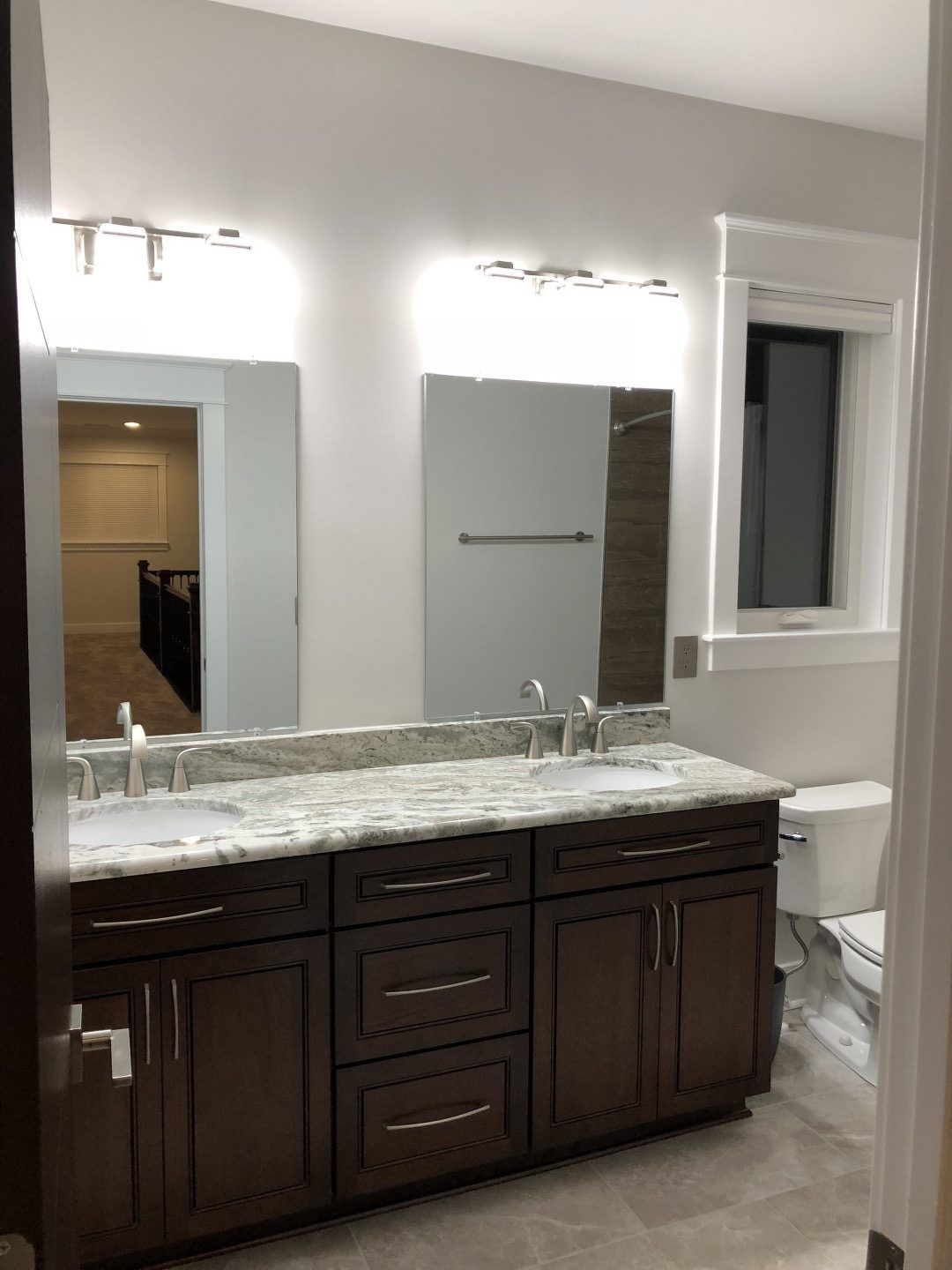 A bathroom with two sinks , a toilet , and a large mirror.