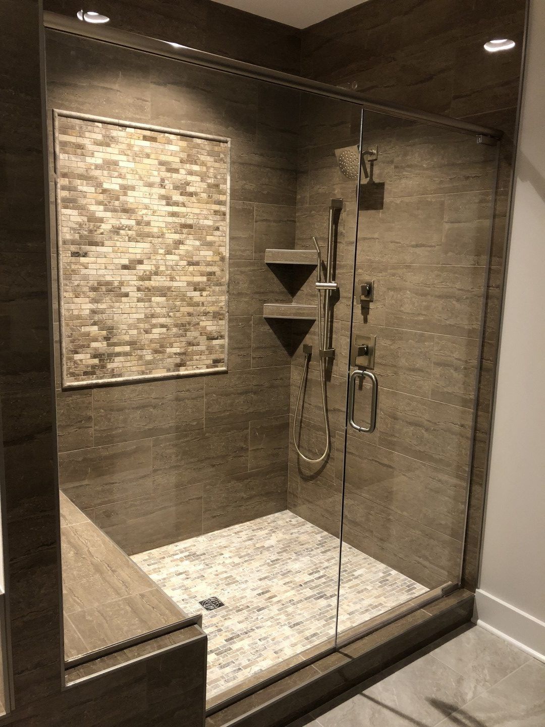 A bathroom with a walk in shower with a glass door.