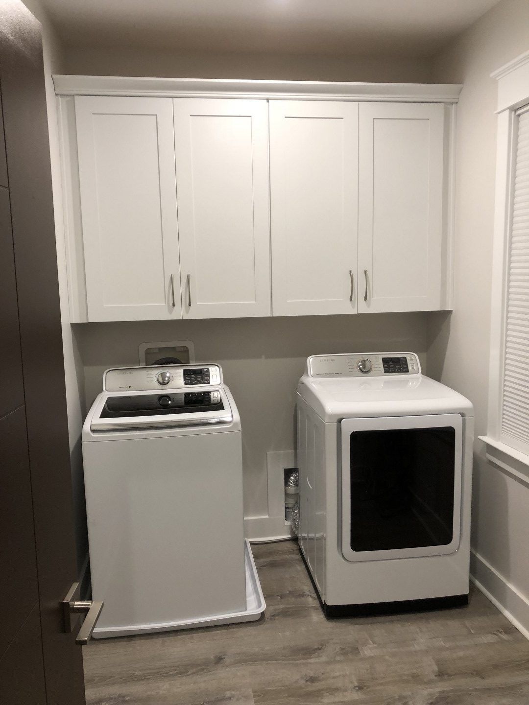 A laundry room with a washer and dryer and white cabinets.