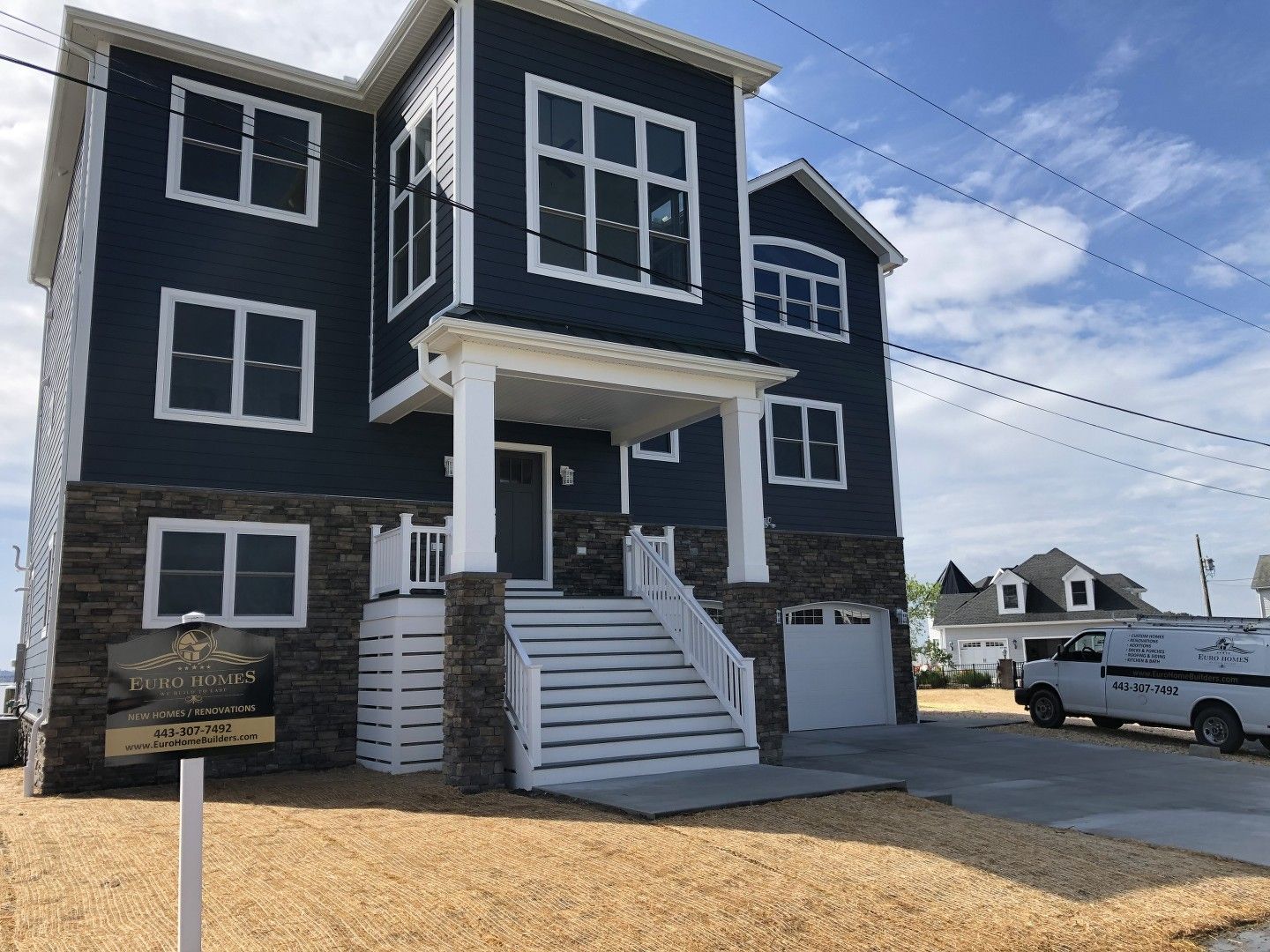 A black and white house with a white van parked in front of it.
