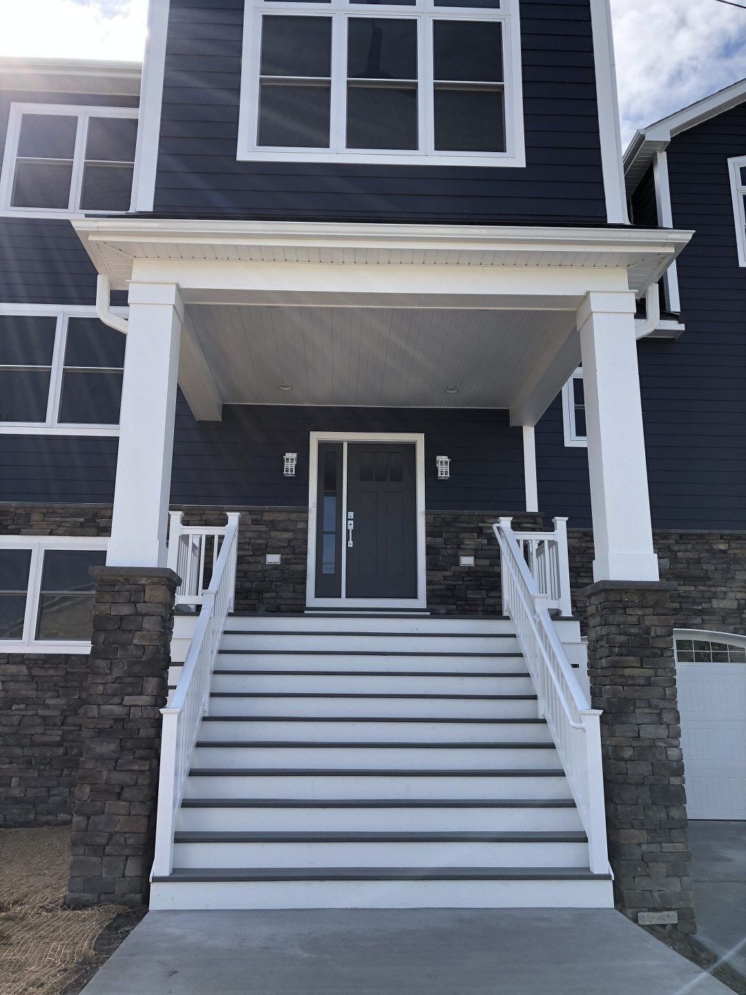 A blue house with white stairs leading up to the front door