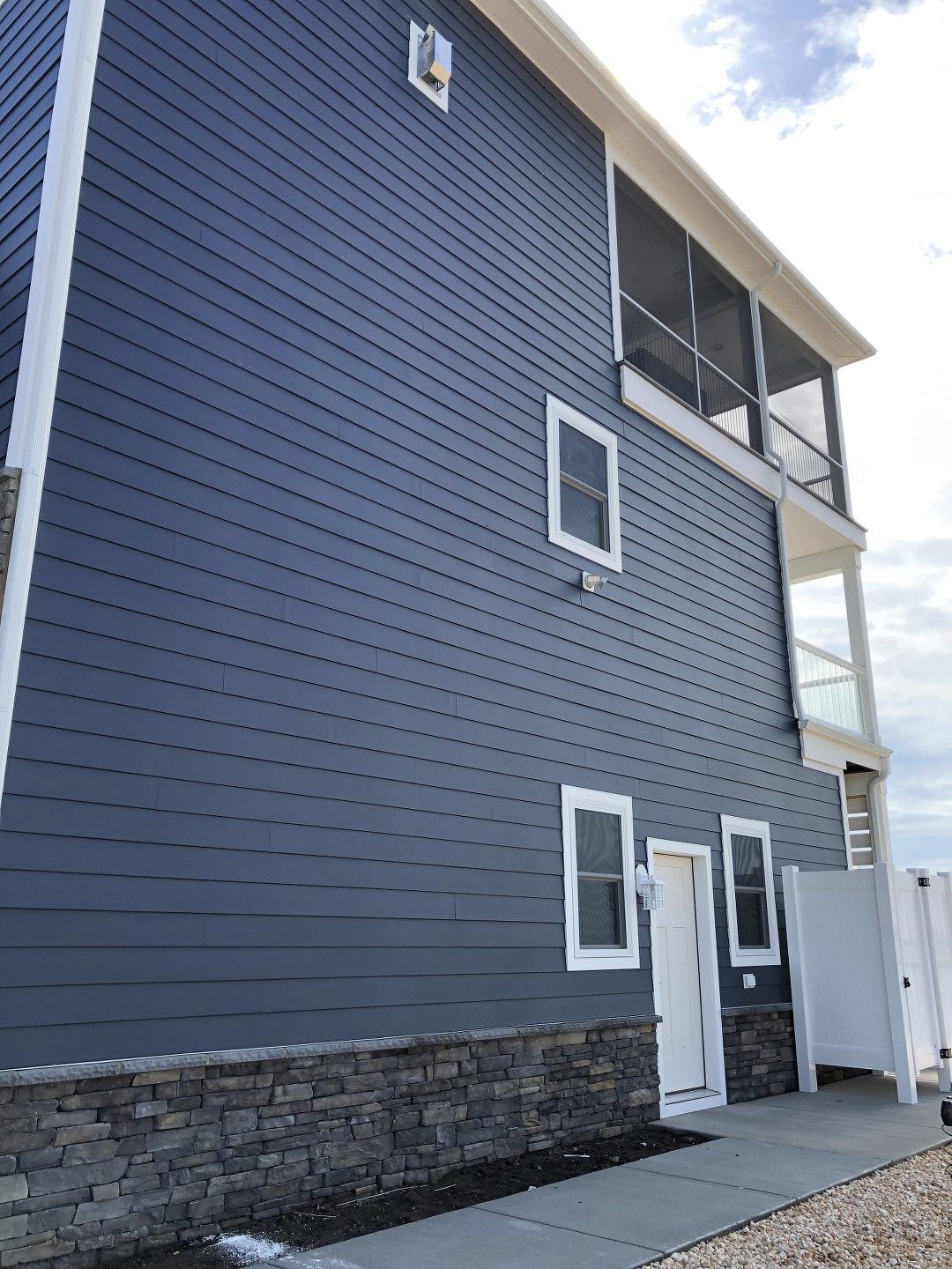 A large blue house with white trim and a screened in porch.