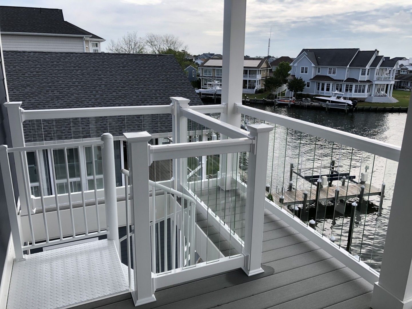 A white deck with a view of the water and a dock.