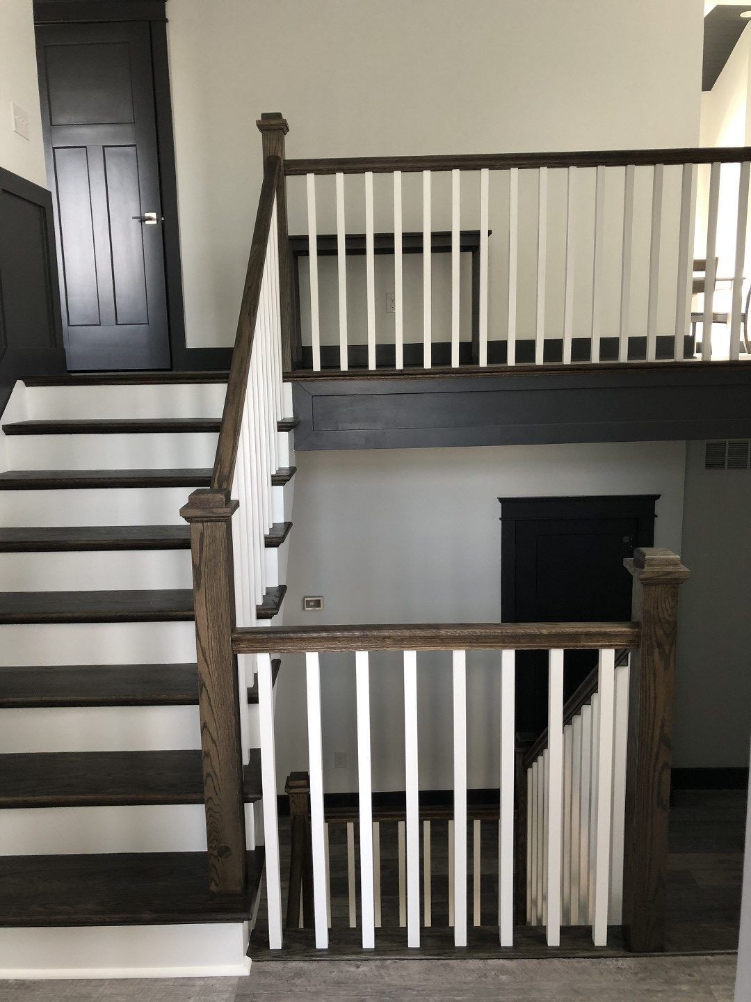 A staircase with a white railing and a black door
