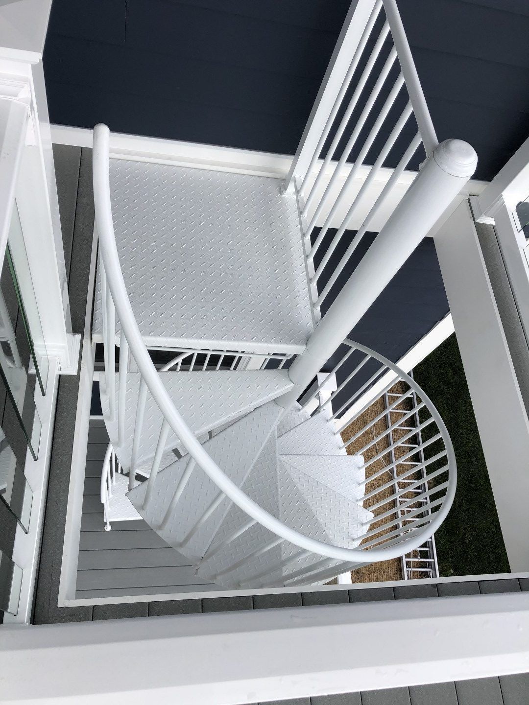 Looking down at a white spiral staircase on a porch.