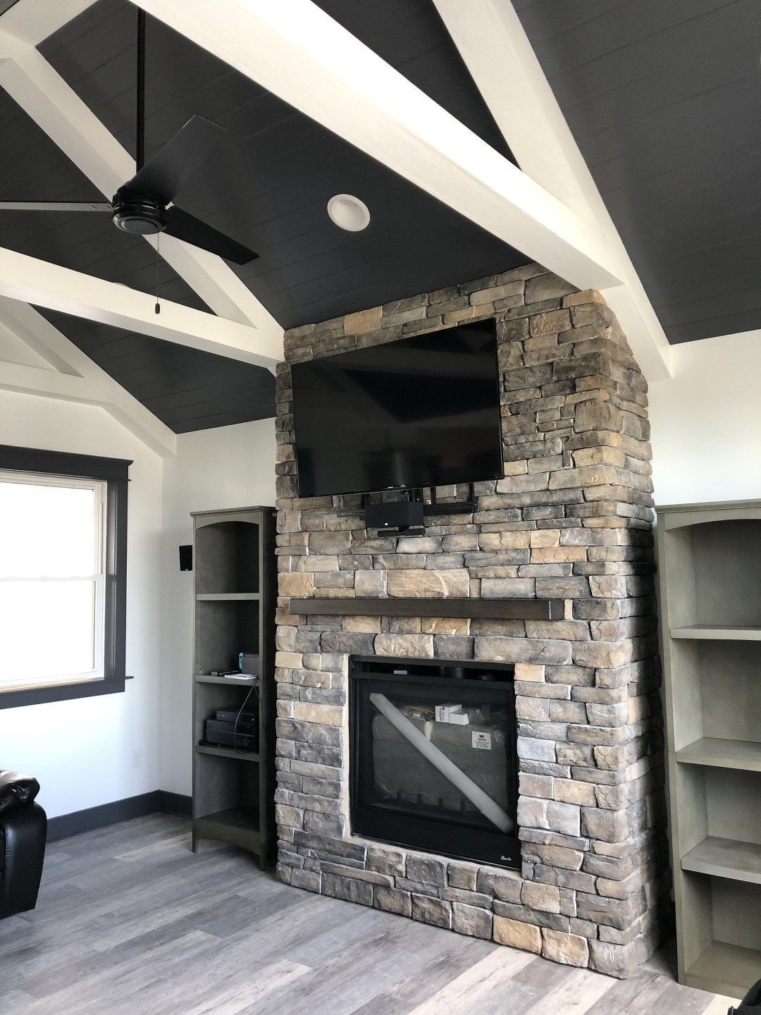 A living room with a stone fireplace and a flat screen tv