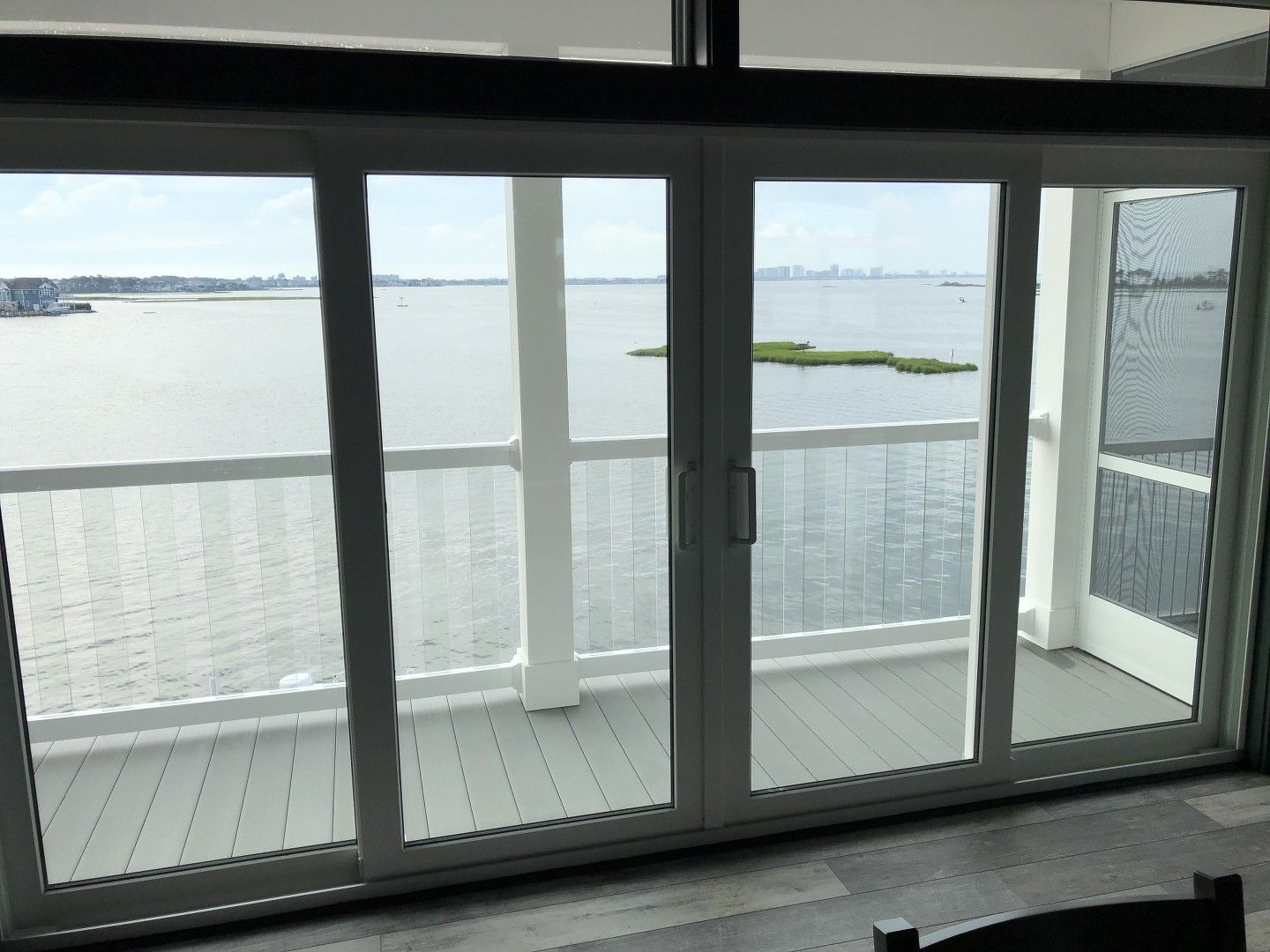 A sliding glass door leading to a balcony overlooking a body of water