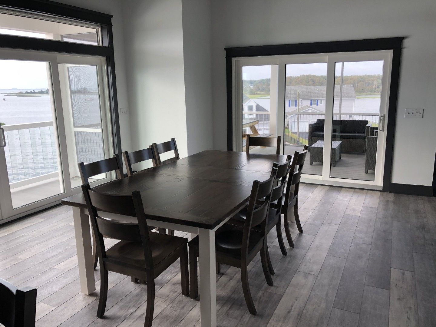 A dining room with a table and chairs and a view of the water.
