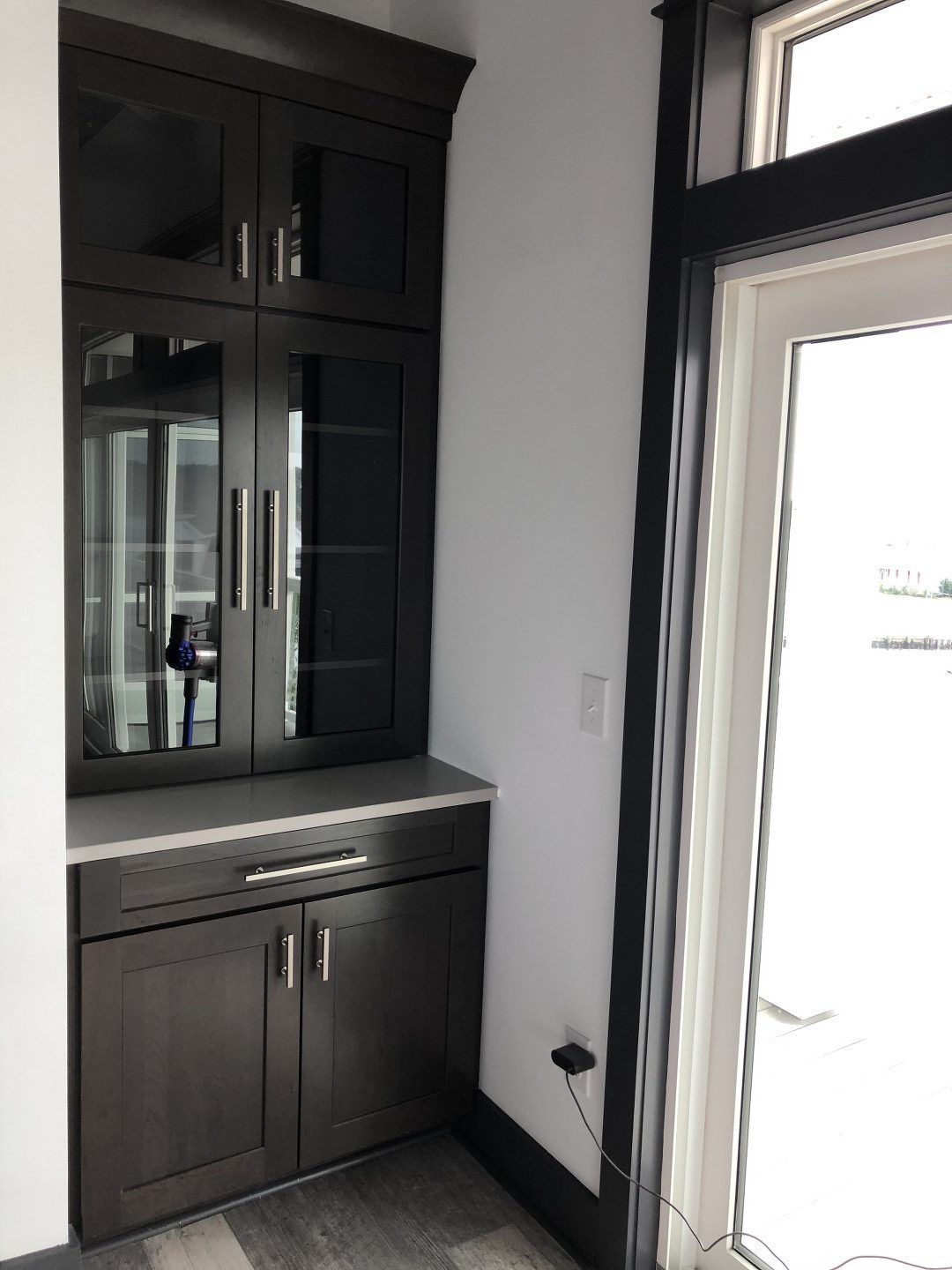 A kitchen with black cabinets and a glass door