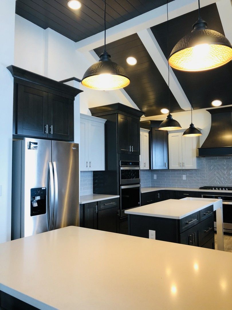 A kitchen with black cabinets and stainless steel appliances