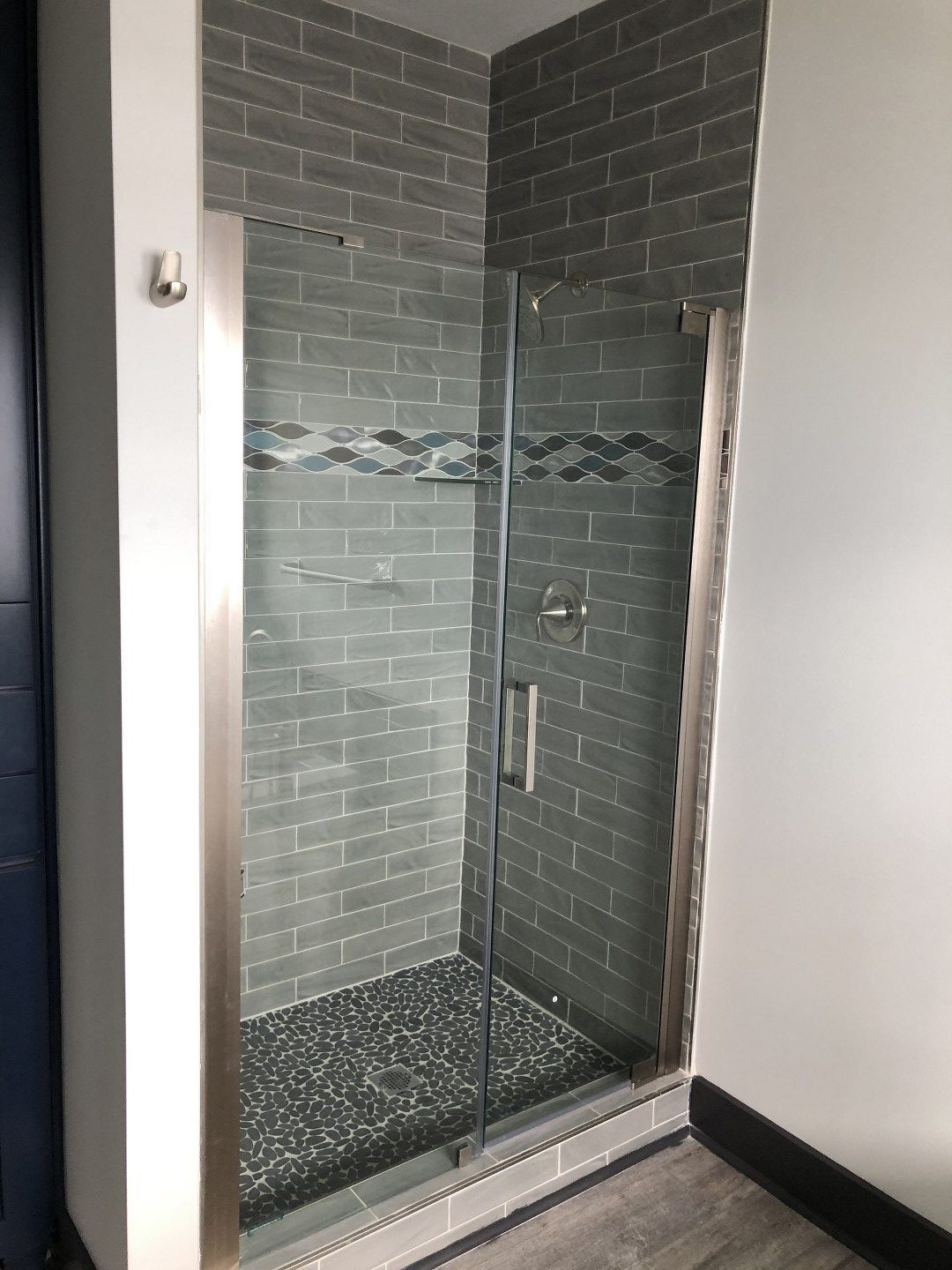 A bathroom with a walk in shower with a glass door.