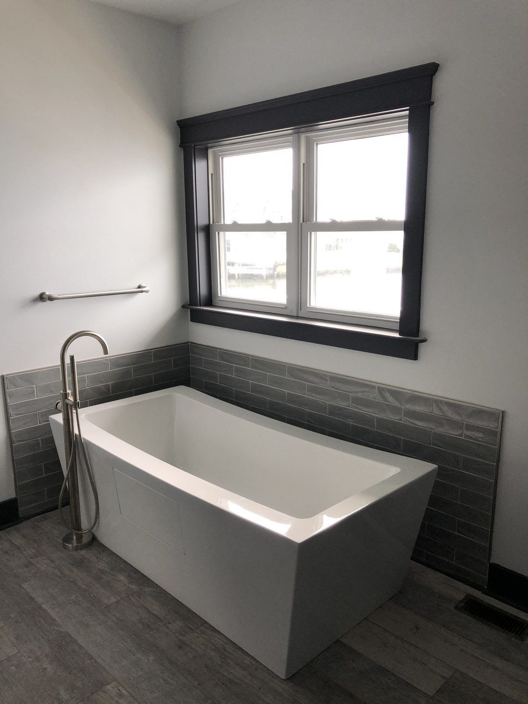 A bathtub in a bathroom next to a window.